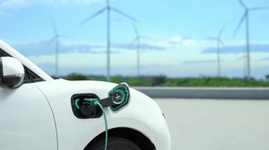 Elektrikli araba, EV şarj istasyonundan enerji alıyor. Rüzgar türbini çiftliğinde EV şarj kablosu kablosunun fütüristik akıllı batarya durum hologramını gösteriyor. Alternatif temiz enerji sürdürülebilirliği. İnceleyin