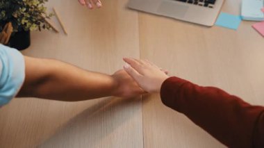 Modern, davetkar bir ortamda sıcaklığı ve bağlantıyı aktaran rahat bir çalışma alanının üzerinde iki elin birbirine uzandığı samimi bir an. SACTR