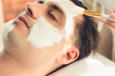 Kaplıca salonunun sakin atmosferi, insan müşterisi modern gün ışığında lüks yüz kremi masajıyla kendini yenileme zevkine kapılıyor. Yüz bakımı ve güzellik konsepti. Sessiz.