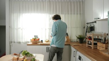 Mutlu baba yemek pişirirken müziğe geçiyor ve modern mutfakta öğle yemeği hazırlıyor. Aktif baba, sebze ve mutfak gereçleri ile çevrili sağlıklı yemek ya da salata yaparken şarkıyla dans ediyor. Pedagoji.
