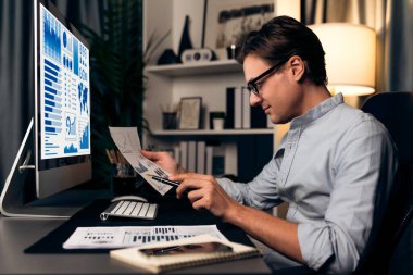 Akıllı bir işadamının elinde kağıt tutarak, gece vakti modern yurt içi ofisindeki şirket toplantısı için müşteri hedefini analiz etmek üzere kalemle paragraf dinamik veritabanı oluşturduğunu düşünüyorum. Bireysel.