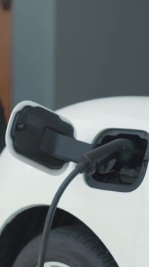Adamın biri evinde elektrikli araç şarj aletinin fişini çekiyor. İlerici bir yaşam tarzında elektrikli araçların kullanımı, temiz ve sağlıklı bir çevreye katkıda bulunur..