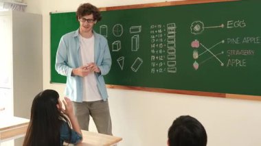 Attractive girl raised his hand and volunteer to write answer on blackboard. Teacher ask for volunteering to answer question while skilled student receive chalk and walk in front of class. Pedagogy.