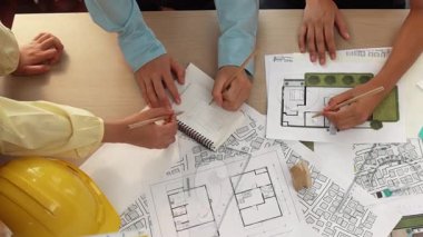 Mimari belge, ölçüm aracı ve ahşap blokların modern ofiste etrafa saçıldığı bir masa üzerinde yapı inşaatı ile ilgili mimar ve güvenlik mühendisi tartışması. Tanımlama.