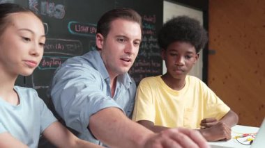 Öğretmen araba modelini seçiyor ve Afrikalı gençler robot sistemi incelerken dizüstü bilgisayar kullanarak araba modellemeyi öğretiyor. Beyaz kız teli tut ve elektronik panoyu tamir etmeye hazırlan. Öğretim