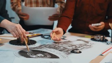 Bir grup mühendis, dinamik bir çalışma alanı atmosferindeki teknik çizimleri ve tartışmaları inceleyen bir türbin tasarım projesinde işbirliği yapıyor. SACTR