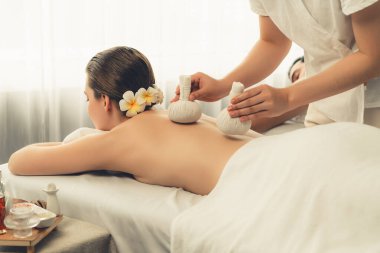 Sıcak bitkisel top spa masaj vücut tedavisi, masör nazikçe bitki torbasını çift müşteri vücuduna bastırıyor. Aromaterapi dinlenme sükuneti ve sükuneti kaplıca salonundaki atmosferi aydınlatıyor. Sessiz.