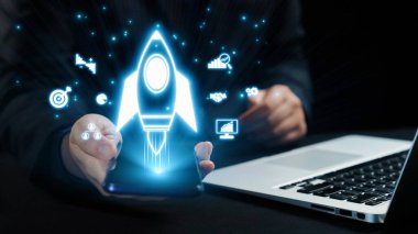 Bir işadamı akıllı telefondan fırlatılan dijital bir roketi, yenilikleri ve modern iş ortamlarında teknolojinin dönüştürücü gücünü sembolize ediyor. Dörtgen