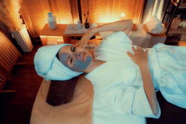 Kaplıca salonunun sakin atmosferi, üst düzey kadın müşteri sıcak mum ışığında kömür kömürü yüz kremi masajıyla kendini yenilemeye çalışıyor. Yüz bakımı ve güzellik konsepti. Sessiz.