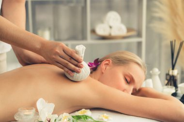 Sıcak bitkisel top spa masaj vücut tedavisi, masör kadın vücuduna nazikçe şifalı bitki torbası bastırıyor. Aromaterapi dinlenme sükuneti ve sükuneti kaplıca salonundaki atmosferi aydınlatıyor. Sessiz.