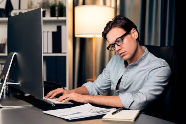 Akıllı iş adamı iş paragrafı dinamik pazarlama analizi planını analiz ediyor. Kağıt kağıtları ve bilgisayar monitörü raporlarını gece evdeki belge verileriyle karşılaştırmak için hazırlıyor. Bireysel.