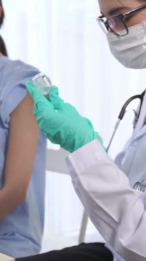 Genç bir kadın, aşı için yetenekli bir doktoru hastanede ziyaret ediyor. Covid 19 ve Coronavirus Aşı Merkezi Hizmet Konsepti .