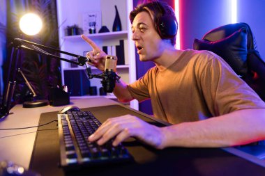 Kazanmak için çevrimiçi oyun oynayan akıllı flama makinesinin sunucu kanalı, neon ışıklı odada seçilen takım yarışması için izleyicilerle birlikte canlı yayında canlı yayında kulaklık takıyor. Bireysel.