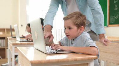 Çeşitli öğrenciler yapay zeka yazılımı kullanırken, Kafkas öğretmeni enerjik çocuğa kodlama konusunda yardım ediyor. Çocuklar oturma ve programlama sistemi. Sevimli bir öğrenci şifreyi öğreniyor. Pedagoji.