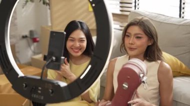 İnternette yayınlanırken gitar kılıfını gösteren ve satan mutlu bir çift. Çekici kız oturma odasında reklam ürünleri için online pazarlama kullanarak yayın yapıyor. Myrmidon.