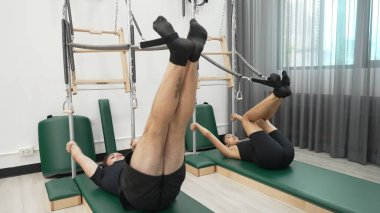 Bir grup müşteri, çekirdek dayanıklılığını ve bacak bağını geliştirmek için Cadillac reformatör makinesinde pilates egzersizleri yapıyor. Sağlıklı müşterilerin daha düşük poz verip kaldırma pozlarının üst görüntüsü. Sağlıklılık. Alışkanlık.