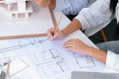 Profesyonel mühendis ev modelini tartartarken, yetenekli tasarımcı da planına yazar. Birlikte çalışmak, işbirliği, işbirliği. Yaratıcı tasarım ve takım çalışması konsepti. Üst Manzara. Tertemiz..