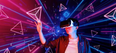 Afrikalı adam, VR kulaklık takıp parlak mavi ve pembe geometrik şekillerde dururken metaevreni keşfetmek için heyecanlanıyor. Oyuncu artırılmış gerçeklik gözlüğü kullanırken oyun oynuyor. Yaratıcılık.