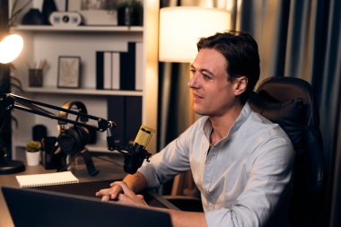 Sunucu kanalı akıllı yayıncı laptopta canlı sosyal medya uygulaması arıyor, kulaklık takıyor ve modern ofis stüdyosundaki mikrofonu kullanıyor. Bireysel.