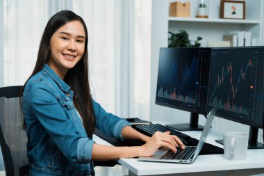 Bilgi teknolojisi geliştirme bölümünden genç bir Asyalı kameraya bakıyor. Kodlama programı veri uygulamalı, kot gömlek giyiyor. Güvenlik analizi ile çevrili iki ekran. Taktik.