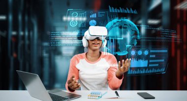 Masada kitap ve dizüstü bilgisayarla ödev yaparken metaevreleri birbirine bağlayan dizüstü bilgisayar ve artırılmış gözlük kullanan bir kız. Öğrenci holograma bakıyor ve yapay zekayı kullanıyor. Yaratıcılık.