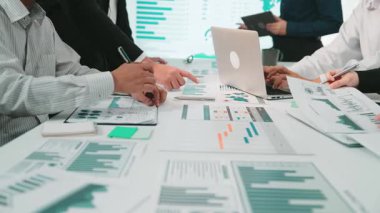 Çeşitli profesyonellerin işbirliği içinde olduğu modern bir ofis sahnesi. Ekip, stratejileri tartışırken ve verilerle ilgili kararlar alırken çizelgeleri ve grafikleri analiz ediyor. SACTR