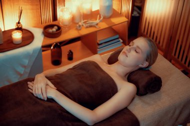 Beyaz kadın müşteri stres önleyici spa masajının keyfini çıkarıyor ve lüks otel ya da otelde sıcak mum ışığında güzellik teniyle eğleniyor. Sessiz.
