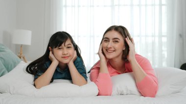 Mutlu Asyalı kız ve akıllı anne kameraya bakarken yatağa uzanıyorlar. Enerjik aile vakit geçirir ve birlikte yatmaya hazırlanır. Sevimli kız ve anne kameraya gülümsüyor sevgi ve şefkat gösteriyorlar. Pedagoji.