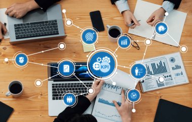 Profesyonel bir ekip, analizi ve işbirliğini geliştirmek için kilit performans göstergelerine odaklanan, teknoloji ve veri görselleştirmelerinden yararlanan bir iş toplantısına katılıyor. Dostluk