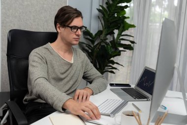 Stresli iş adamı günü modern ofisteki dinamik borsa grafiğine bakıyor, veri tabanı bilgisayarını ve bilgisayarını evden çalışırken karşılaştırıyor. Bireysel.