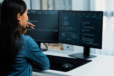 Genç Asyalı bilişim geliştiricisi güzel poz için online bilgi topluyor. Kodlama programı verileriyle birlikte kotlu tişört giyiyor. Güvenlik analizi ile çevrili iki ekran. Taktik.