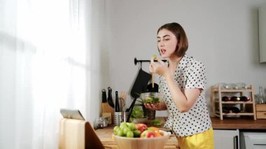 Mutlu genç anne mutfakta dururken salata kasesine sebze koydu. Çekici beyaz bir kadın yemek pişirmekten ve sabah taze organik yemek yapmaktan ya da ev yemeği yapmaktan zevk alır. Pedagoji.