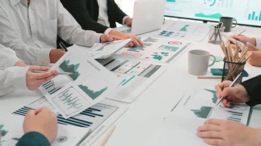 Çeşitli bir iş ekibi, belgeler üzerinde gösterilen çizelge ve grafikleri analiz ederek, veri odaklı karar verme stratejilerine odaklanarak, işbirlikçi bir toplantıya katılıyor. SACTR