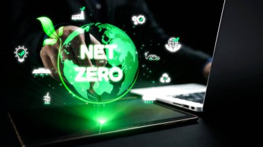 Parlayan yeşil bir kürenin dijital temsili ile etkileşime giren bir el, net sıfır emisyon elde etmenin ve dünya çapında çevre bilincini artırmanın önemini vurguluyor. Dörtgen