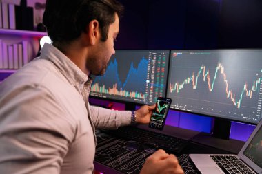 Akıllı tüccar işadamı, karanlık oda gecesinde neon ışıklı ofisteki arama pazarında yüksek kârla ekranda bilgisayar ve bilgisayar üzerinde dinamik borsa yatırımları üzerinde yoğunlaşıyor. Tahmin et..