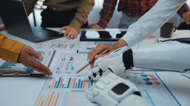 Bu görüntü, ofis ortamında insanlar ve robotlar arasındaki sinerjiyi yakalar, veri analizi, takım çalışması ve modern iş stratejilerine odaklanır.