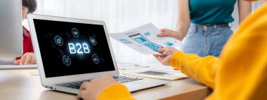 İş adamı B2B peyzajında geziniyor, iş-iş bağlantılarını geliştirmek için kullanım teknolojisi kullanıyor. B2B etkileşimini yeniden şekillendiren keşifler, iş-iş stratejilerinde yenilikleri yönlendiren araçlar. canlı