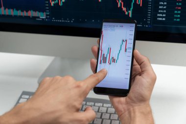 Akıllı borsa yatırımcıları ekranda akıllı telefon ile piyasa borsasını işaret ederek dizüstü bilgisayarın yanı sıra en yüksek dinamik yatırım oranını göstererek, modern işyerindeki veri planlamasına odaklanıyorlar. Bireysel.