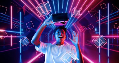 VR gözlüklü ve parlayan geometrik şeklinde duran sıradan giysili adam. Oyuncu artırılmış gerçeklik teknolojisi kullanarak metaevrene girmek ve kulaklık takmak konusunda heyecanlı. Yaratıcılık.