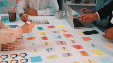 Çeşitli bir ekip, yapışkan notlar ve teknolojik aletlerle dolu ortak çalışma alanındaki renk paletleri ve tasarım elemanlarını analiz ederek yaratıcı bir beyin fırtınası yaptı. SACTR