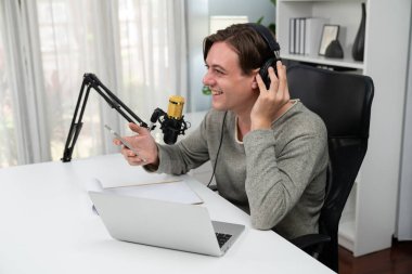 Sunucu kanalı, gülümseyen akıllı yayıncı kaydı, senaryosu ve akıllı telefonuyla sosyal medyada sohbet programı, kulaklık takarak modern ev stüdyosundaki video flamalarını kaydediyor. Bireysel.