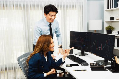 Başarılı gülümseyen Asyalı iş ortakları borsa veritabanında kârlı bir proje için el ele tutuşuyorlar. Yan görüntüdeki modern ev ofisinde resmi takım elbise giyiyorlar. İnfobahn.