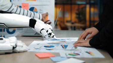 İnsan eli, modern çalışma alanındaki verileri analiz ederken robot kolla işbirliği yapar ve karar verme konusundaki teknoloji ve insan uzmanlığının sinerjisini gösterir. Noogenesis