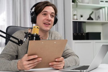 Akıllı yayıncının sunucu kanalı canlı sosyal medya yayını ile dinleyicilere senaryo okuyarak, kulaklık takarak modern ev stüdyosundaki video flamalarını kaydediyor. Bireysel.