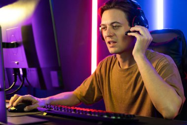 Kazanmak için çevrimiçi oyun oynayan akıllı flama makinesinin sunucu kanalı, neon ışıklı odada seçilen takım yarışması için izleyicilerle birlikte canlı yayında canlı yayında kulaklık takıyor. Bireysel.