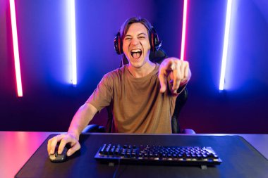 Kazanmak için çevrimiçi oyun oynayan akıllı flama makinesinin sunucu kanalı, neon ışıklı odada seçilen takım yarışması için izleyicilerle birlikte canlı yayında canlı yayında kulaklık takıyor. Bireysel.