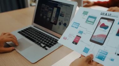 Mobil uygulama için kullanıcı arayüzü prototipini ofis çalışanlarına sunan harika bir şirket çalışanı. UX UI tasarımcısı kağıt üzerinde simge tasarımının işlevini açıklıyor. Sinerjik