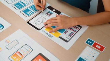 Mobil uygulama için kullanıcı arayüzü prototipi ya da masadaki program modeliyle birlikte web sitesi planlaması yapan bir şirket çalışanı. UX UI tasarımcısı kullanıcı dostu arayüz planını dikkate alır. Sinerjik