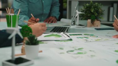 Modern bir ofisteki çeşitli bir ekip, çevre dostu verileri analiz ediyor ve etkili iş büyümesi ve çevresel bakım için sürdürülebilir stratejiler geliştiriyor. SACTR