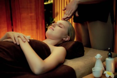 Beyaz kadın stres önleyici kafa masajı yapmaktan ve lüks otel veya otelde sıcak mum ışığında yüz güzelliği eğlencesi yapmaktan zevk alıyor. Sessiz.